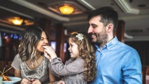 two adults with little girl feeding woman
