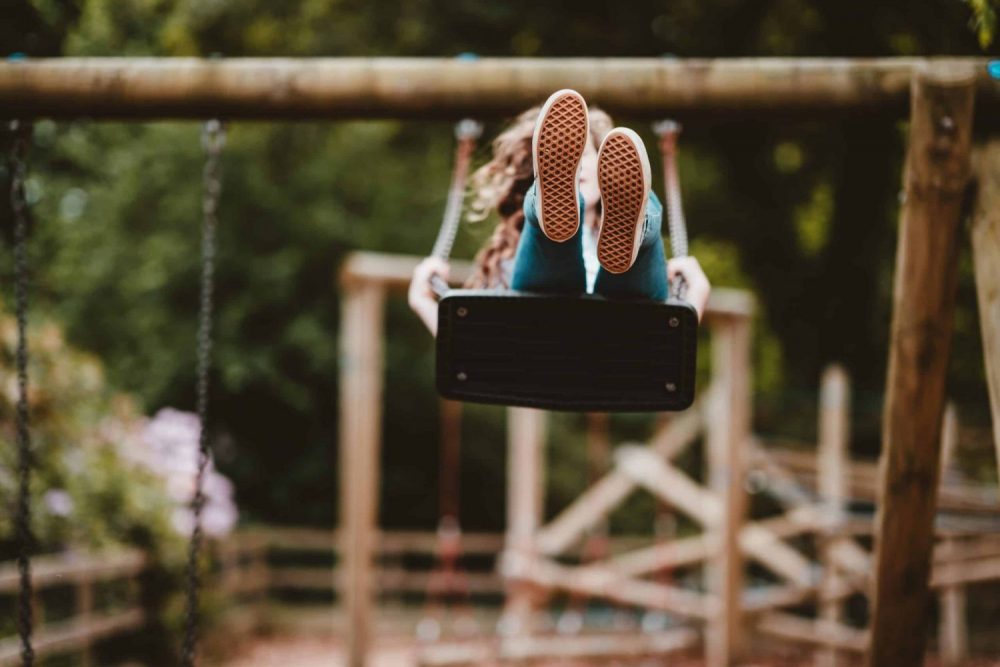 child swinging high on swing, front