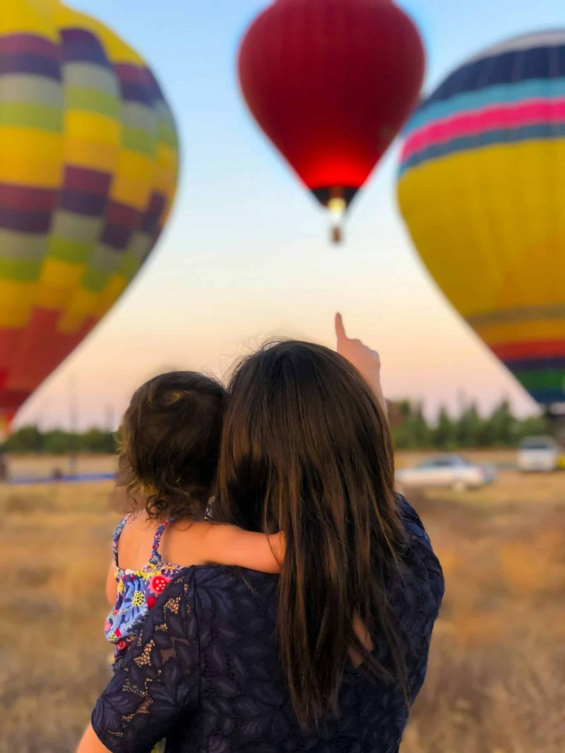 woman and baby watch air balloons