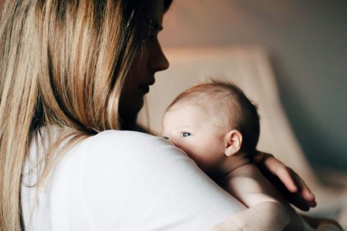 woman with shadowed face hugs baby