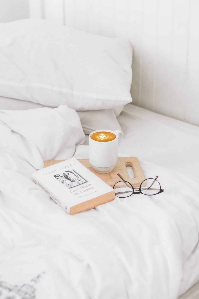 notebook, drink on white bed
