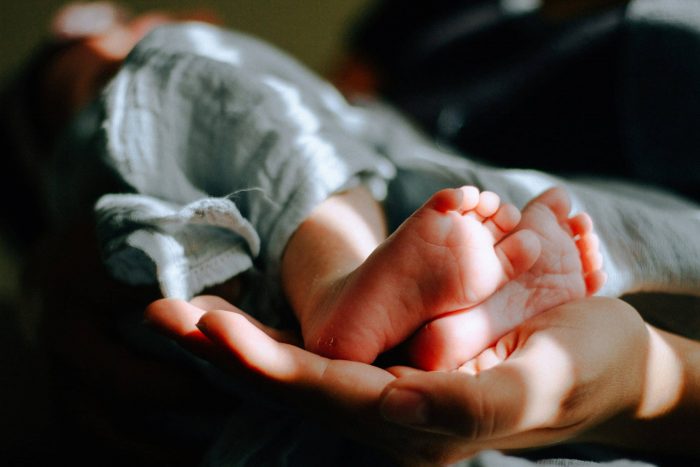 adult hand supporting baby feet